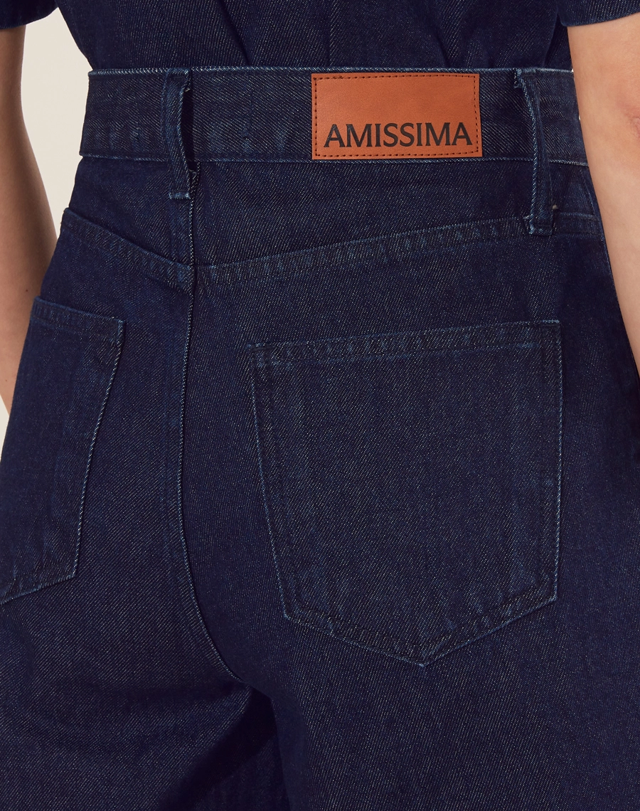 Bermuda confeccionada em jeans de lavagem escura com cintura alta.<br/>
 Apresenta uma modelagem solta e confortável, garantindo liberdade de movimento.<br/>
 Possui bolsos frontais funcionais e detalhes em costura contrastante que adicionam um toque moderno à peça. <br/>
Fechamento por zíper e botão de casa, tornando-se perfeita para compor looks casuais e elegantes.<br/>