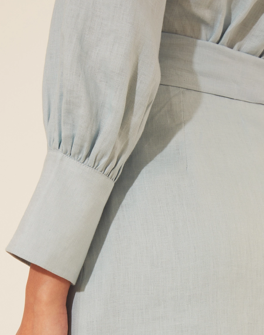 Vestido Midi Gina confeccionado em Cambraia de Linho, possui decote V transpassado com gola esporte. <br/>
Detalhe plissado em sua saia.<br/>
Faixa para laço na cintura, com forro curto. <br/>
Fechamento por ziper invísivel lateral.