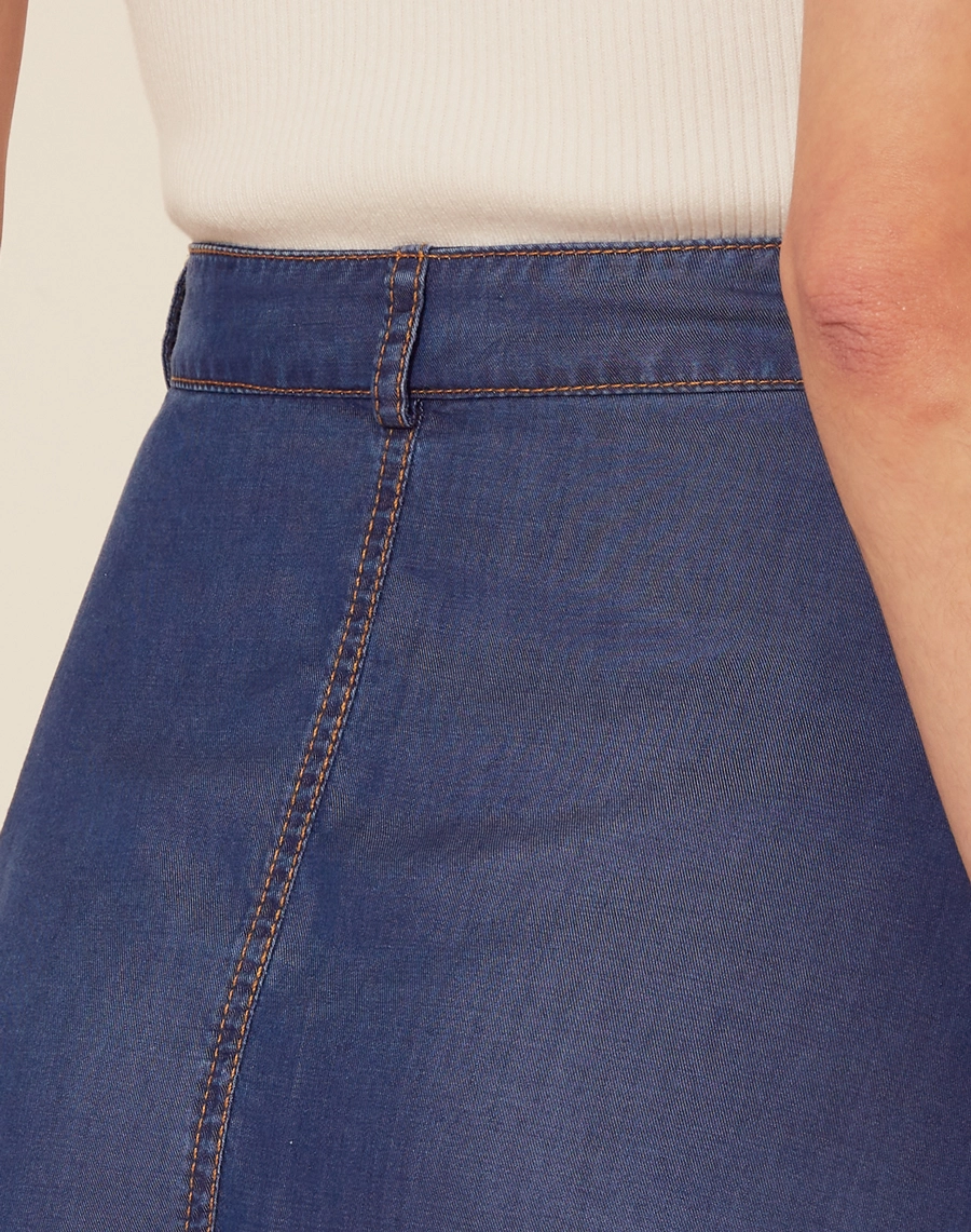 Saia Midi Malva confeccionada em Jeans possui modelagem evasê (ampla), cintura alta e dois bolsos laterais estilo faca.<br/>
Seu fechamento é frontal por botão de casa.<br/>
