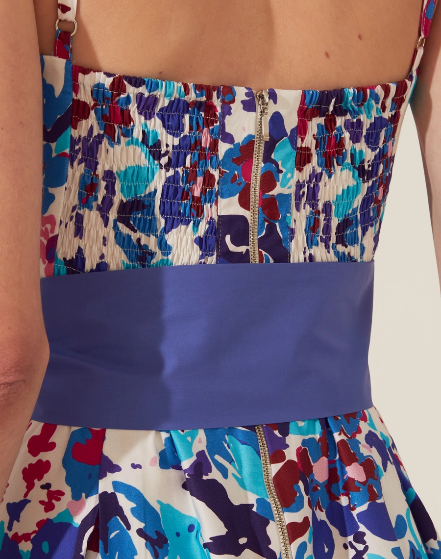 Vestido Midi Les Cedres é confeccionado em tecido AE (Aled Estampado) de Algodão, que oferece suavidade ao toque e respirabilidade.<br/>
A estampa vibrante mistura tons de azul, roxo e vermelho, trazendo uma atmosfera alegre e contemporânea. <br/>
O vestido possui alças finas e ajustáveis que destacam os ombros, enquanto o decote coração moldado realça o busto. <br/>
A cintura é acentuada por uma faixa azul fixa que pode ser ajustada de diferentes formas, com fechamento por zíper invisivel lateral.<br/>