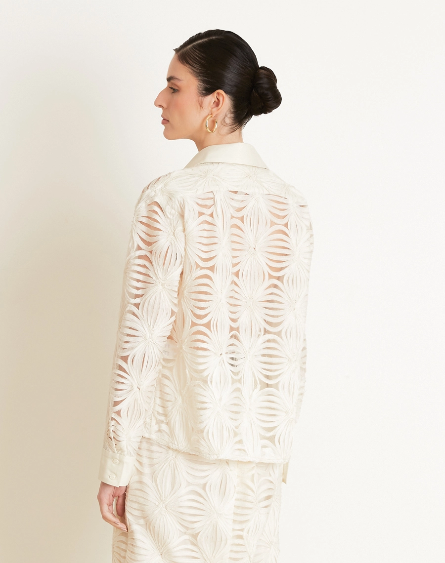 A Camisa Palmo é confeccionada em Tule bordado, um tecido leve e delicado, com transparência sutil e desenhos em relevo que enriquecem a peça com um visual sofisticado e feminino.