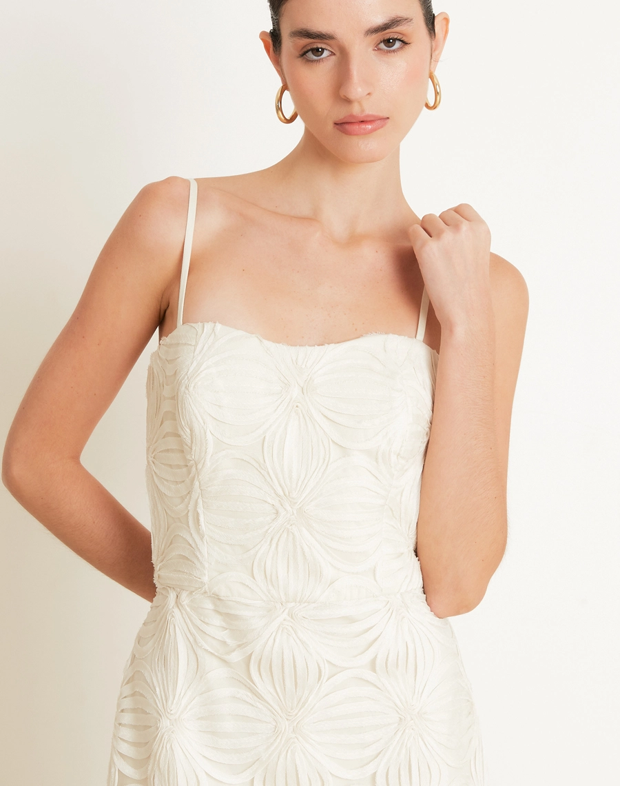 O Vestido Midi Palmo é confeccionado em Tule bordado, um tecido leve e delicado, com transparência sutil e desenhos em relevo que enriquecem a peça com um visual sofisticado e feminino.